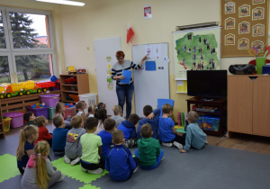 Dzieci siedzą przed tablicą, słuchają przekazu nauczycielki